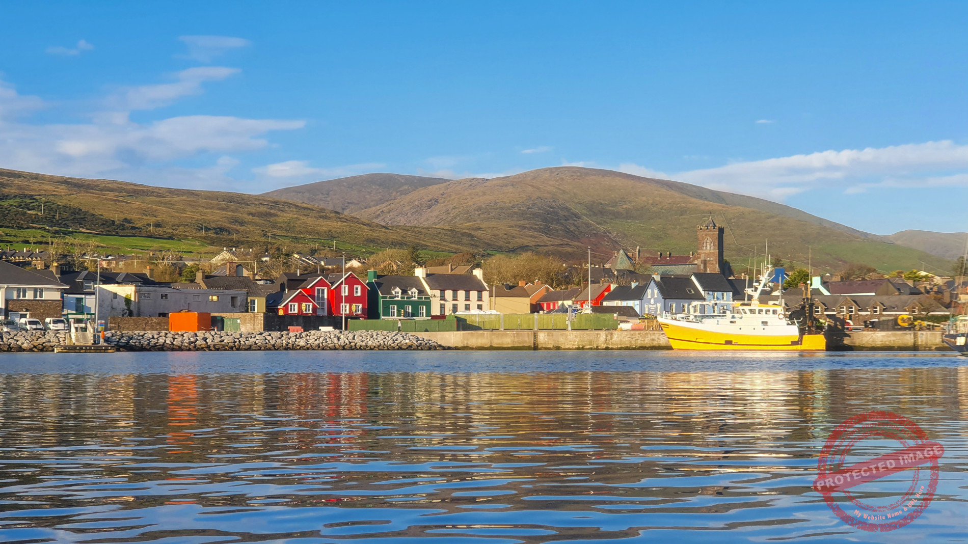 Fishing harbour of Dingle with colorful boats and houses.